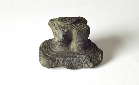 Lisciatoio in pietra riproducente in miniatura un nuraghe quadrilobato.